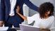 A woman at a desk pushes away a man A woman at a desk pushes away a man