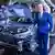 Volkwagen CEO Herbert Diess standing next to a car on an assembly line