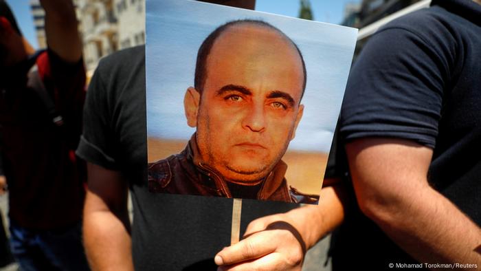 Man holding placard with picture of Nizar Banat