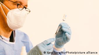 Врач набирает в шприц вакцину от коронавируса