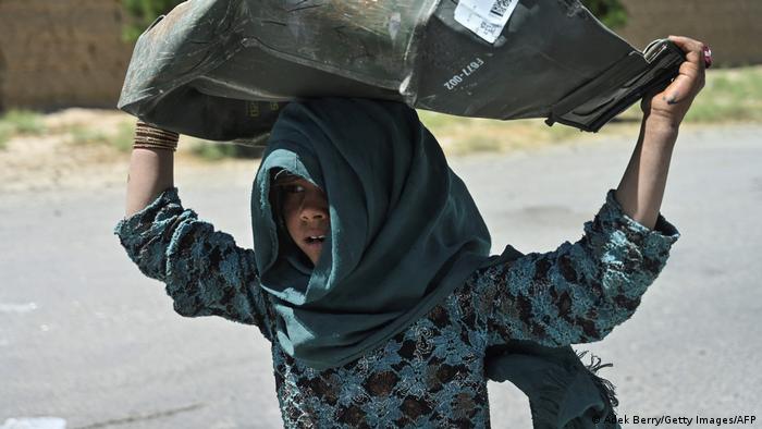 Anak gadis ini memulung peti logam rongsokan dari tempat sampah Bagram.