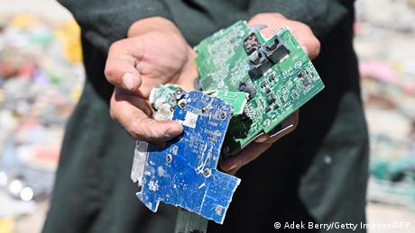 A man holding electronic waste he found at the dump
