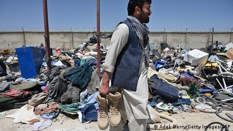 A man holds shoes as he selects valuable items at a recycling workshop near the Bagram Air Base