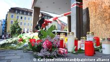 Ein Polizist steht neben Kerzen und Blumen vor einem geschlossenen und abgesperrten Geschäft in der Innenstadt. In Würzburg hat ein Mann am Vortag wahllos Menschen mit einem Messer attackiert. Drei Menschen starben, mindestens fünf wurden schwer verletzt.