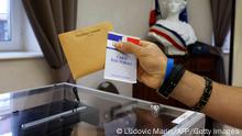 A voter holds an electoral card and a ballot before voting at a polling station in Etaples, northern France, for the second round of the French regional elections on June 27, 2021. (Photo by Ludovic MARIN / AFP) (Photo by LUDOVIC MARIN/AFP via Getty Images)