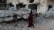 A Palestinian woman holding her son walks past her house that was destroyed by an Israeli air strike in June. There is another boy say on a bit of debris. The building next door is also highly damaged. A Palestinian woman holding her son walks past her house that was destroyed by an Israeli air strike in June. There is another boy say on a bit of debris. The building next door is also highly damaged.