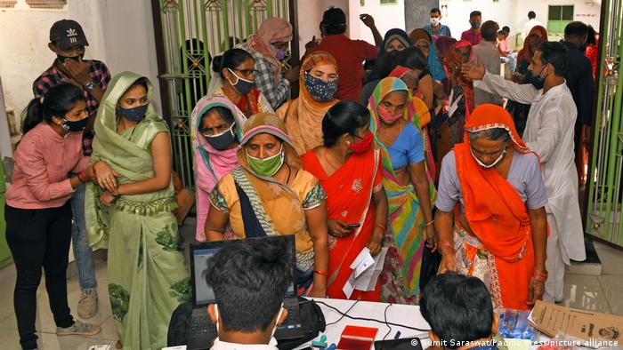 Indian women wait in line for a vaccine
