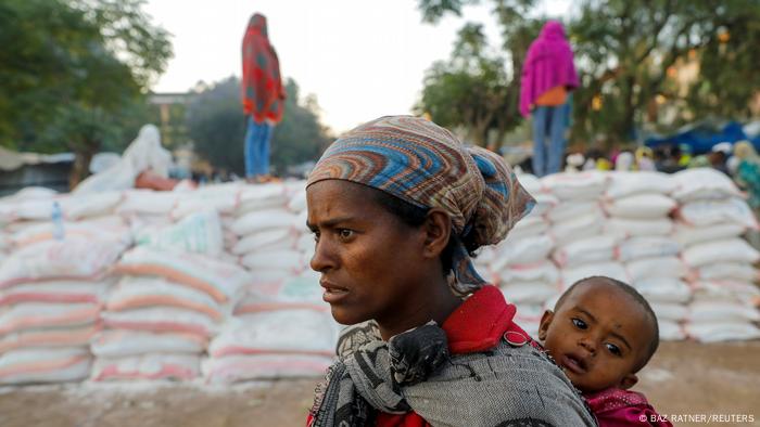 A displaced Tigrayan woman and her child queiing for food