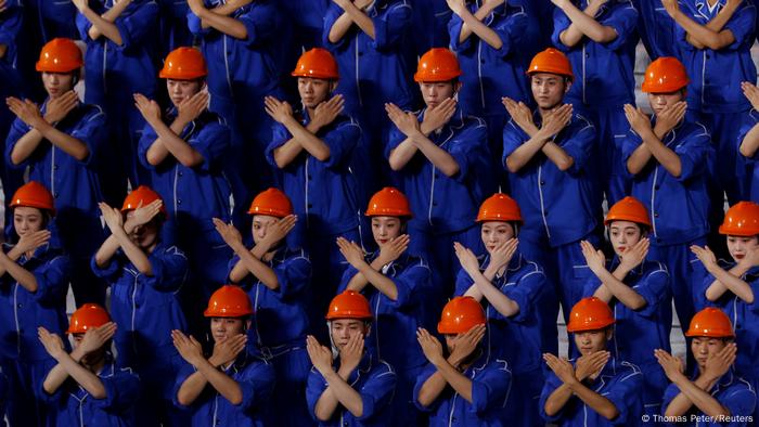 People in orange hard hats cross their arms