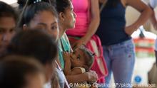 In this Feb. 8, 2020 photo, a mother breastfeeds her toddler as Nicaraguan asylum-seekers wait for the arrival of the Deputy High Commissioner for the UN Refugee Agency, or UNHCR, in Upala, Costa Rica. The UNHCR has also launched a pilot program with Costa Rica's social security system that would allow 6,000 asylum-seekers to enroll in the country's health care network and access public medical centers like any Costa Rican. (AP Photo/Moises Castillo)