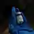 Mão com luva azul segurando frasco de vacina
