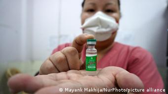 A healthcare worker in New Delhi holds a vial of Covishield
