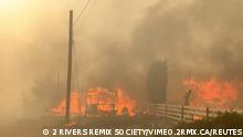 Flames rise from a burning building along a street during a wildfire in Lytton, British Columbia, Canada June 30, 2021 in this still image obtained from a social media video on July 1, 2021. 2 RIVERS REMIX SOCIETY/via REUTERS THIS IMAGE HAS BEEN SUPPLIED BY A THIRD PARTY. MANDATORY CREDIT. NO RESALES. NO ARCHIVES. MUST CREDIT 2 RIVERS REMIX SOCIETY / VIMEO.2RMX.CA.