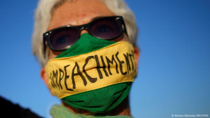 Mulher com faixa verde e amarela com a palavra impeachment