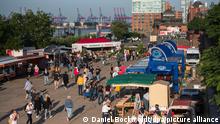 Besucher gehen über den Hamburger Fischmarkt. Die berühmte Touristenattraktion hat erstmals nach 15-monatiger Zwangspause unter Auflagen wieder geöffnet.