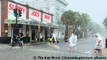 Eine Gruppe Menschen watet das Hochwasser einer überschwemmten Straße vor Sloppy Joe's Bar. Ausläufer des Tropensturms Elsa, mit Sturmböen und starken Regenschauern, haben zu Überschwemmungen geführt. +++ dpa-Bildfunk +++