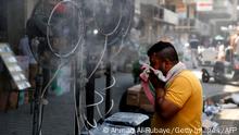 A man stands by fans spraying air mixed with water vapour deployed by donors to cool down pedestrians along a street in Iraq's capital Baghdad on June 30, 2021 amidst a severe heat wave. (Photo by AHMAD AL-RUBAYE / AFP) (Photo by AHMAD AL-RUBAYE/AFP via Getty Images)