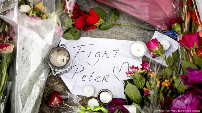 Des fleurs et des bougies entourent une note qui dit Fight Peter, illustrée d'un cœur 