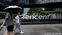 This photo taken on May 26, 2021 shows people walking past the Tencent headquarters in the southern Chinese city of Shenzhen, in Guangdong province. (Photo by NOEL CELIS / AFP)