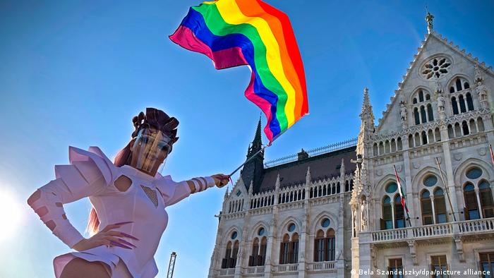 A drag queen outside the Hungarian parliament holds a rainbow flag