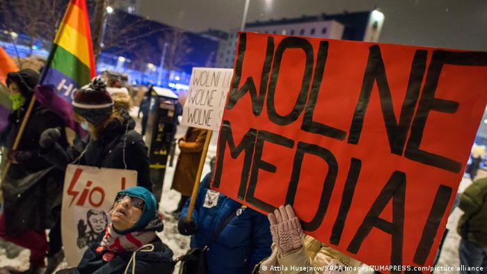 A sign at a protest says Wolne Media! — Polish for Free Media — near a rainbow flag