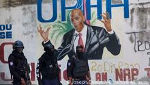 Police stand near a mural featuring Haitian President Jovenel Moise, near the leader’s residence where he was killed by gunmen in the early morning hours in Port-au-Prince, Haiti, Wednesday, July 7, 2021. (AP Photo/Joseph Odelyn)
