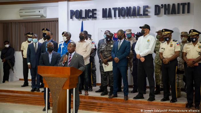 El presidente interino Claude Joseph, en el centro, habla con los periodistas durante una rueda de prensa para mostrar a los sospechosos capturados.