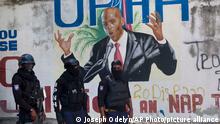 Police stand near a mural featuring Haitian President Jovenel Moise, near the leader’s residence where he was killed by gunmen in the early morning hours in Port-au-Prince, Haiti, Wednesday, July 7, 2021. (AP Photo/Joseph Odelyn)