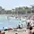 Pessoas se banham e tomam sol na praia de Barceloneta, em Barcelona