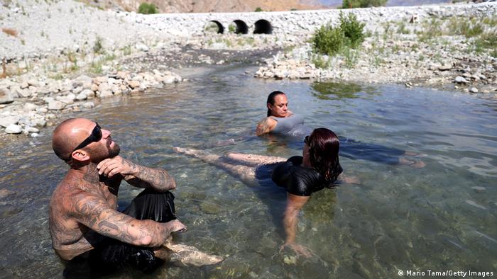 Drei Menschen kühlen sich in einem Fluss ab