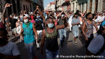 Milhares de cubanos saíram às ruas para protestar contra a escassez de alimentos e medicamentos. Multidão com pessoas que caminham de braços erguidos e com máscaras em rua de Havana.
