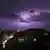 Foto noturna mostra raios no céu de uma cidade