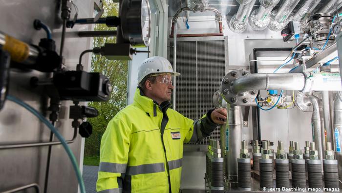 Seorang pekerja dengan jaket hi-vis kuning berdiri di dalam pembangkit listrik-ke-gas di Hamburg