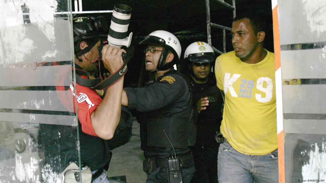 Un policía trata de parar a un periodista con su cámara de fotos en Caracas. Un policía trata de parar a un periodista con su cámara de fotos en Caracas.