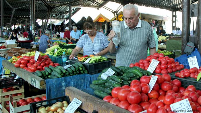 Market scene with fruit and vegetables and a man holding a bottle of water