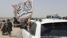 People wave a Taliban flag as they drive through the Pakistani border town of Chaman on July 14, 2021, after the Taliban claimed they had captured the Afghan side of the border crossing of Spin Boldak along the frontier with Pakistan. (Photo by Asghar ACHAKZAI / AFP) (Photo by ASGHAR ACHAKZAI/AFP via Getty Images)