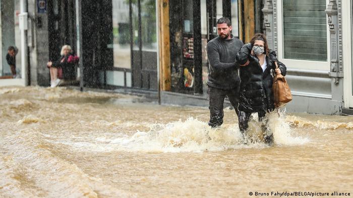 И Белгия бе засегната от силни дъждове. В провинция Лиеж съобщават за поне две жертви. На снимката двама души от град Спа, само на 35 км от германската граница, се опитват да преминат през една от централните улици. 