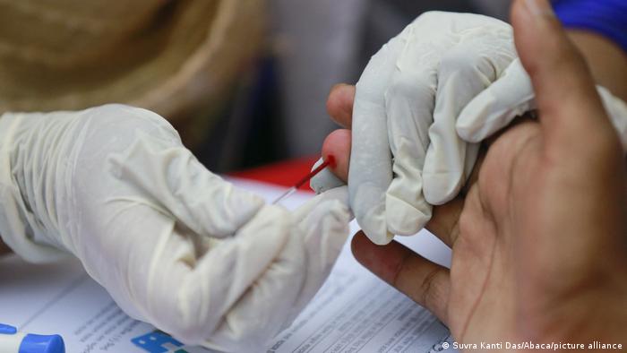 A person's finger being pricked by a medical professional to test them for HIV