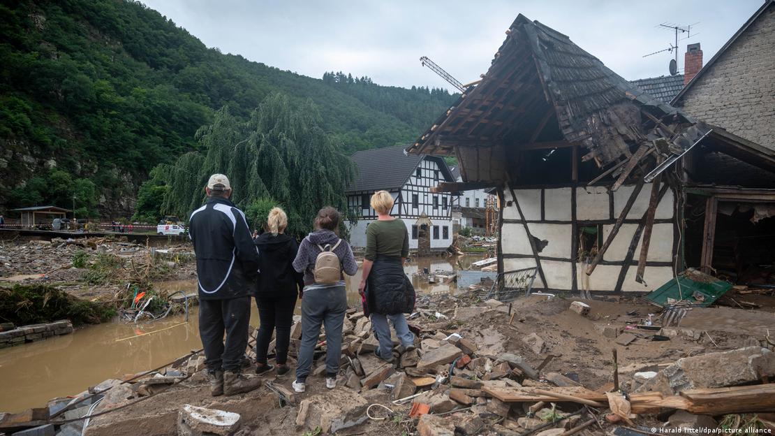 Família olha para um vale com casas de estilo enxaimel destruídas 