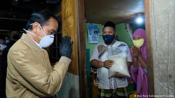 Widodo mengucapkan selamat tinggal kepada sebuah keluarga setelah mengantarkan bahan makanan ke rumah mereka di Jakarta