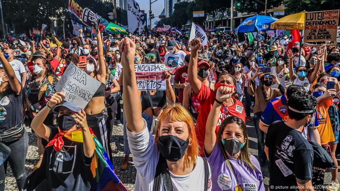 Foto mostra muitas pessoas protestando. Elas usam máscara. Algumas erquem o punho e outras, cartazes. Foto mostra muitas pessoas protestando. Elas usam máscara. Algumas erquem o punho e outras, cartazes.