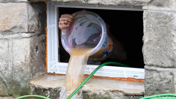 Sacando agua de un sótano con un balde.