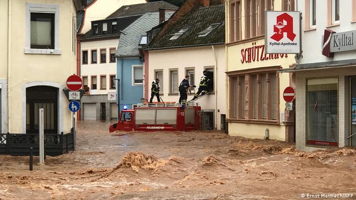Firemen standing on the roof of their vehicle climb into an inundatetd house in the flooded Ehrang neighbourhood in Trier, western Germany