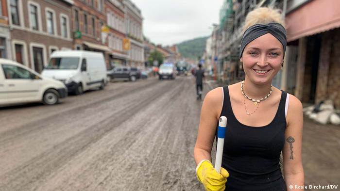 Oceane Nourdinjer stands in a muddy street with a broom