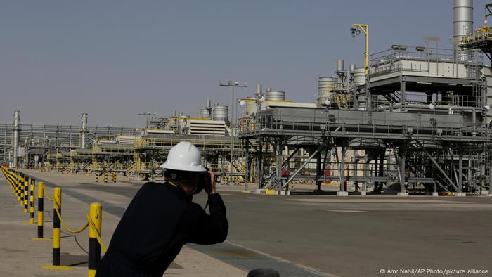 A man in a helmet takes photos in the Khurais oil field