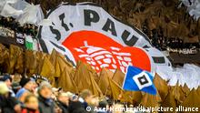 Fußball: 2. Bundesliga, Hamburger SV - FC St. Pauli, 23. Spieltag. Fans von St. Pauli haben ein Vereinsbanner auf der Tribüne entrollt. Davor ist eine HSV-Fahne zu sehen. +++ dpa-Bildfunk +++