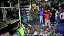 People and security forces gather at the site of a bombing in Wahailat market in Sadr City, Iraq, Monday, July 19, 2021. A roadside bomb attack targeted a Baghdad suburb Monday, killing at least 18 people and wounding dozens of others at a crowded market, Iraqi security officials said. (AP Photo/Khalid Mohammed)