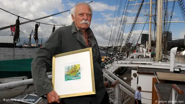 Janosch hält auf der Rickmer Rickmers eine Radierung von ihm in der Hand. (Foto: Angelika Warmuth dpa/lno)