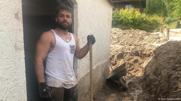 Florian local pose avec une pelle tout en creusant la boue de sa maison