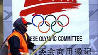 Ein Straßenkehrer vor dem offiziellen Olympiade Logo in Peking